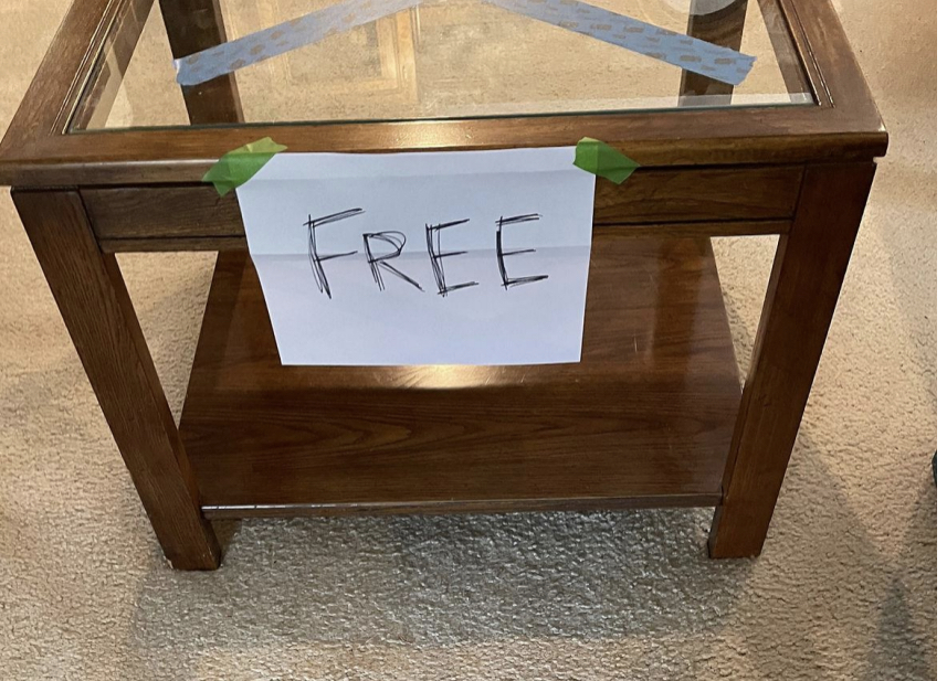 Brown wood table with glass top and free sign taped on it.