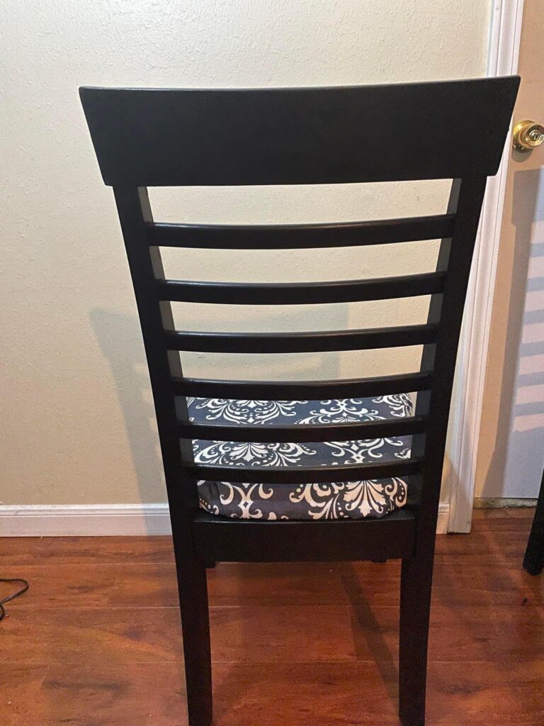 Back of wooden chair painted black. Curbside chairs painted black and upholstered with upcycled shower curtains. DIY Furniture hack.